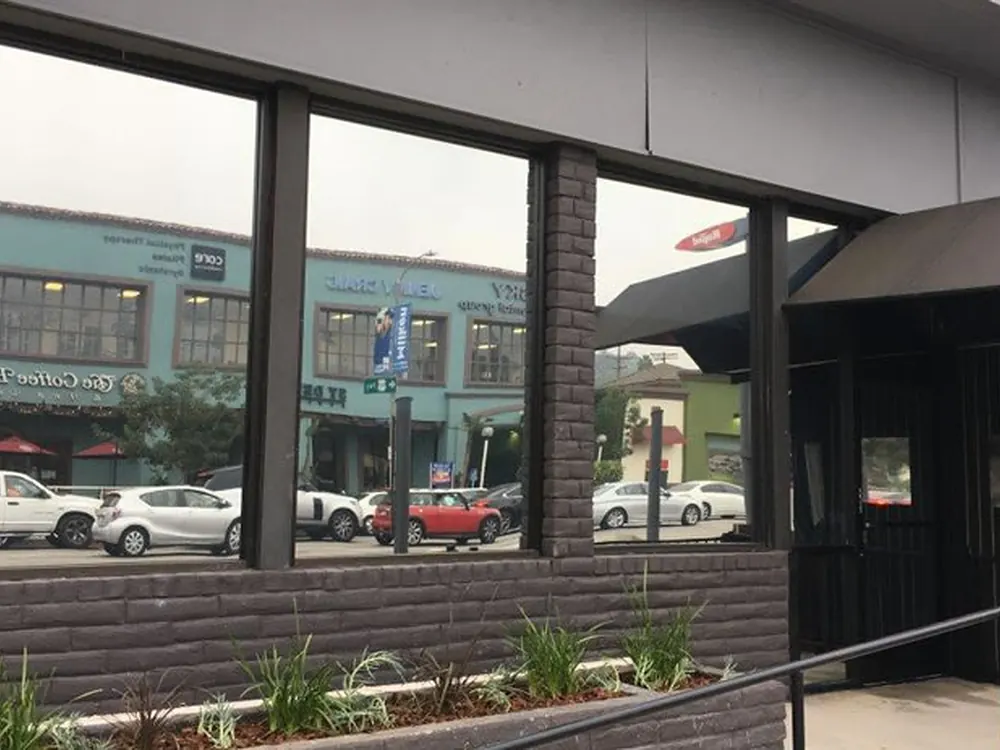 Tinted storefront glazing set into brick, mirroring the street scene outside.