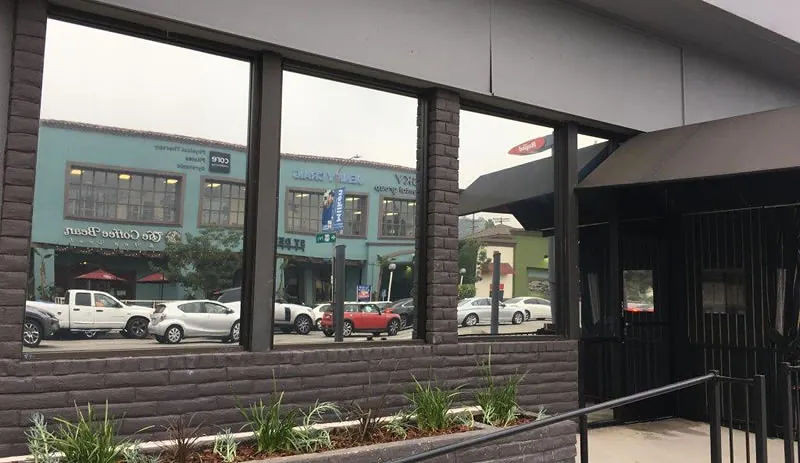 Tinted storefront glazing set into brick, mirroring the street scene outside.